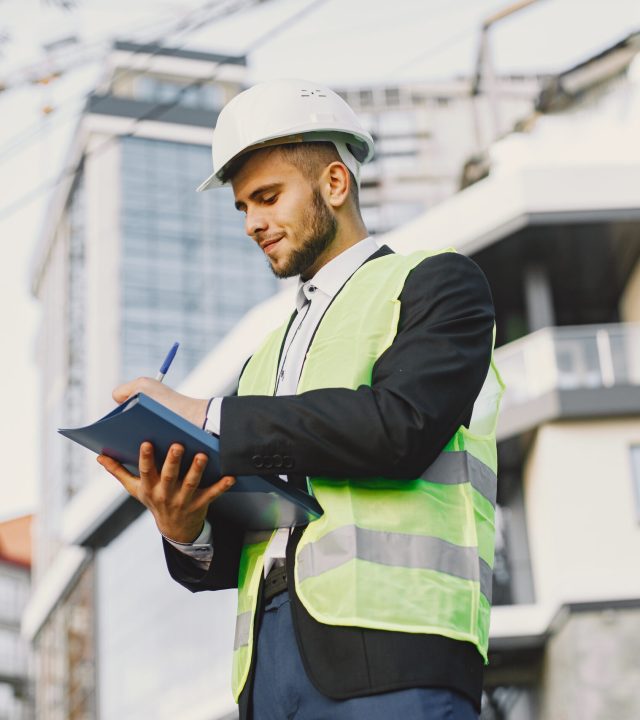 Man in builder uniform holding older. Looking at building plan. Modern city setting.